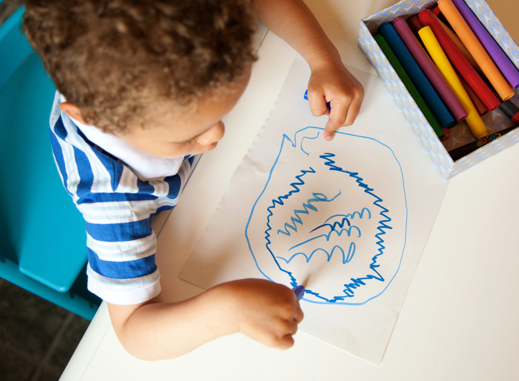 A young boy is drawing with colored pencils.