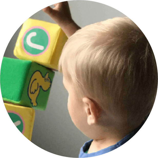 A young child playing with blocks in front of a mirror.